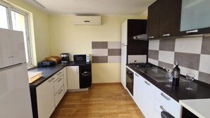 A compact kitchen with a refrigerator, microwave, stove, and a coffee maker. - Apartment with Two Bathrooms (Orebic)