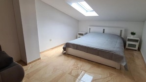 A bedroom with a skylight, a bed, a nightstand, and a small plant. - Apartment with Two Bathrooms (Orebic)