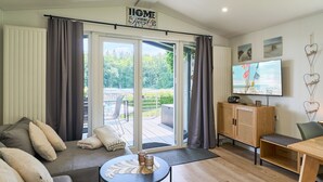 Una sala de estar moderna con sofá, mesa de centro, televisor y puerta corrediza de vidrio que da a un espacio exterior.