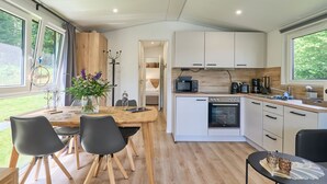 Una cocina moderna con una mesa de comedor de madera, sillas negras y un horno empotrado.