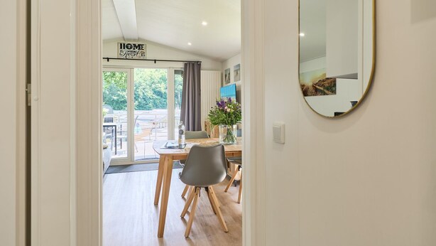 Un interior moderno con zona de comedor, un espejo grande y un letrero que dice 'HOME IS WHERE THE HEART IS'.