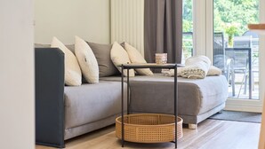 Una sala de estar moderna con un sofá gris, una mesita y una cesta de mimbre.