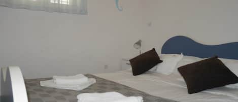 A hotel room with a bed, pillows, a lamp, and towels.