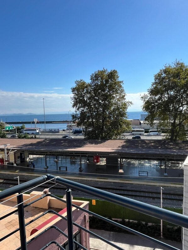 Un quai de gare offrant une vue dégagée sur la mer et les montagnes lointaines.