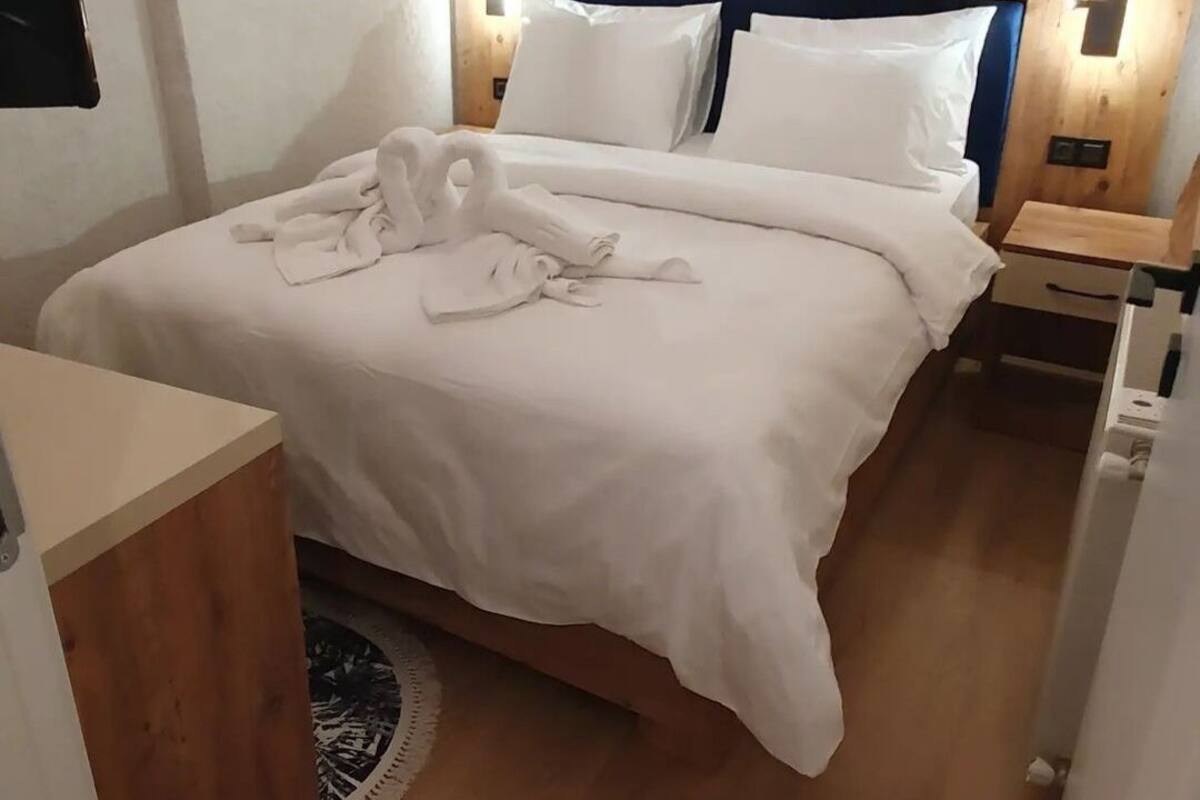A hotel room with a bed, a bedside table, a nightstand, and a round rug.