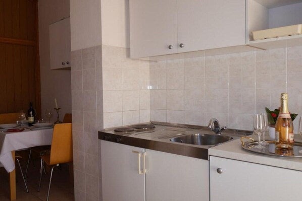 A modern kitchen with a built-in stove, sink, and white cabinets.