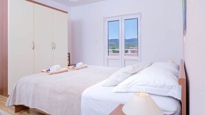 Ein Schlafzimmer mit Bett, Kleiderschrank, einem Fenster mit Aussicht und einer Deckenleuchte.