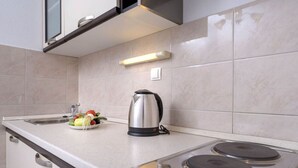 A modern kitchen with a stainless steel stove, a kettle, and a sink with fresh vegetables. - One Bedroom Apartment with Balcony and Sea View 2 (Vrboska)