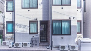 A multi-story building with a tiled facade, multiple air conditioning units, and a door with a sign above it. - Zenith Shinjuku Hinoki Building B (Tokyo)
