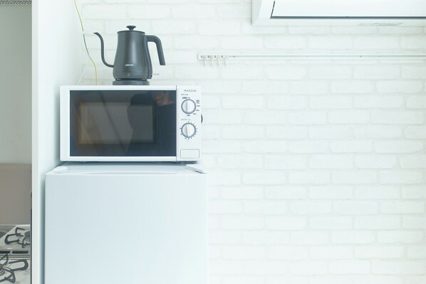 A white microwave oven with a black pot on top, placed on a white refrigerator. - Zenith Shinjuku Hinoki Building B (Tokyo)
