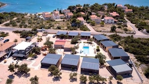 An aerial view of a coastal resort with multiple buildings, a swimming pool, and a clear view of the sea. - Classic Two Bedroom Mobile Home with Terrace and Sea View (Br2) (Pirovac)