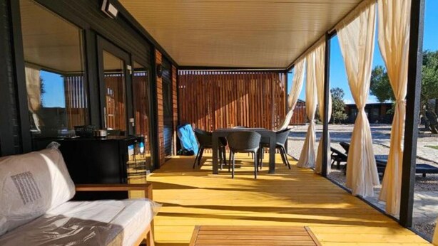 A covered outdoor area with a wooden deck, a table with chairs, and a sofa. - Classic Two Bedroom Mobile Home with Terrace and Sea View (Br2) (Pirovac)
