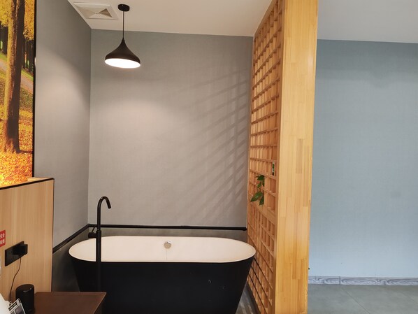 Un baño moderno con una bañera independiente, un lavabo empotrado y una lámpara colgante.