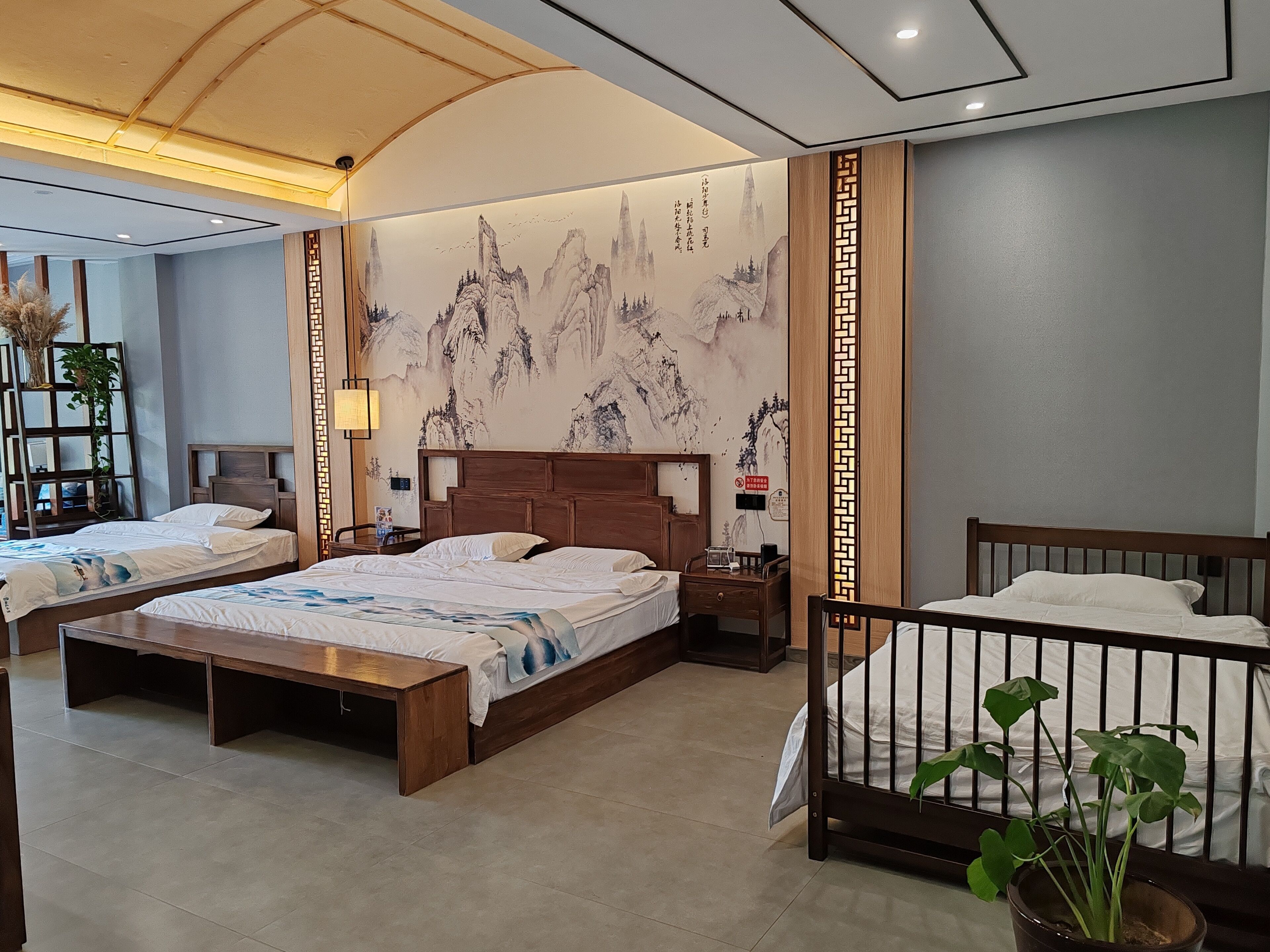A hotel room with two beds, a wooden headboard, a large mural, and a traditional Chinese-style partition.