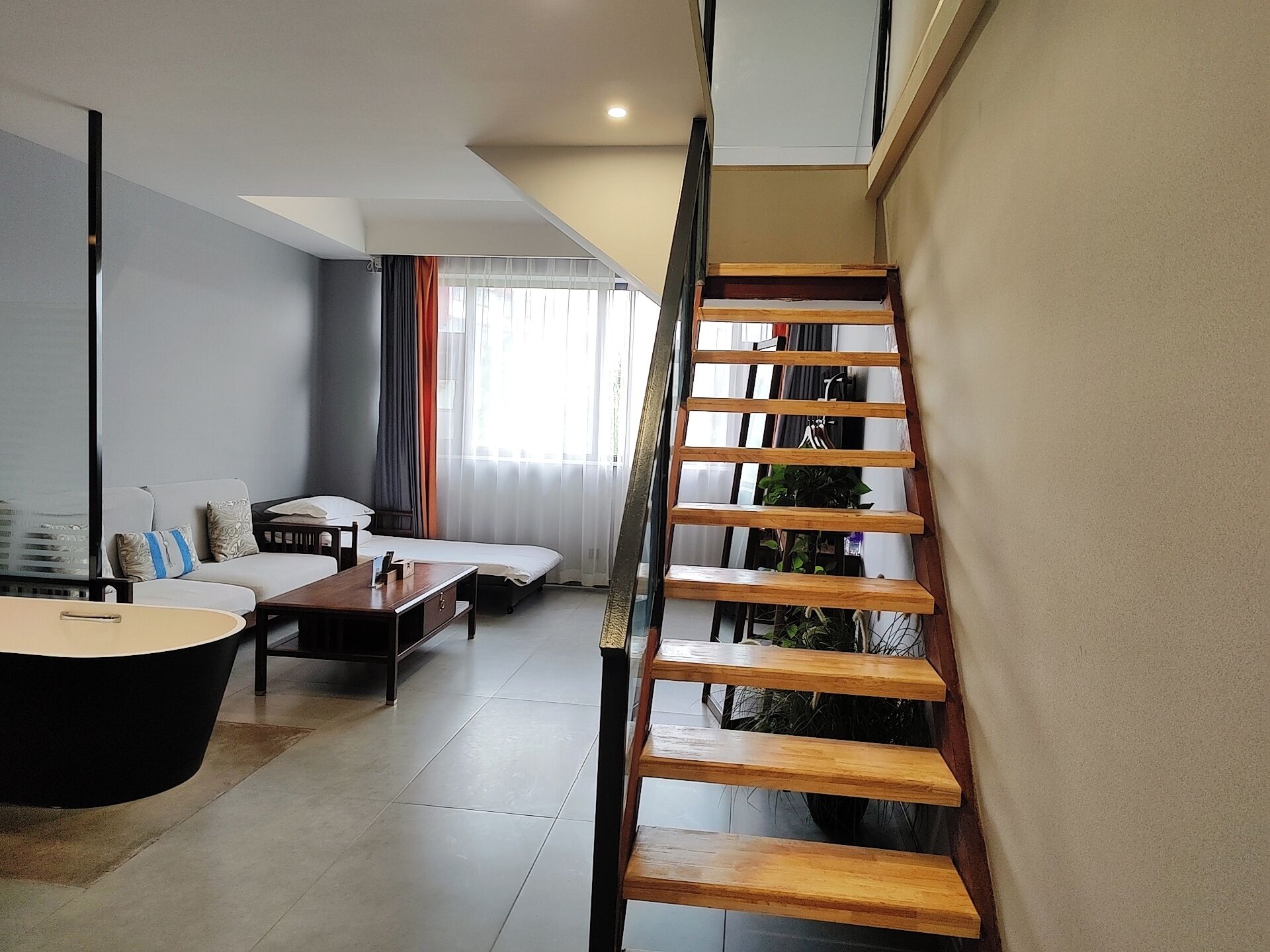 Una sala de estar moderna con una escalera, un sofá, una mesa de centro y una mesa de comedor.
