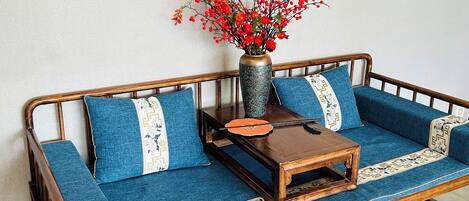 A wooden sofa with blue cushions and a decorative vase with red berries.