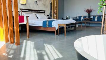 A modern hotel room with a large bed, a seating area with a bench, and a large window allowing natural light.