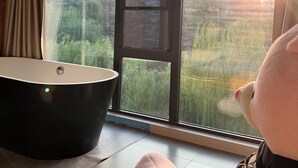 Ein Zimmer mit einem großen Fenster, einer Badewanne und einem weichen Stofftier.