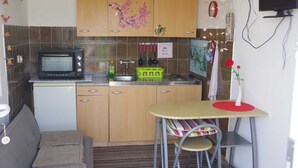 Une cuisine compacte équipée d’un four à micro-ondes, d’un évier et d’un petit coin repas avec une table et des chaises.