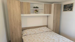 Une chambre à coucher avec un lit, une armoire en bois et une étagère avec des plantes.