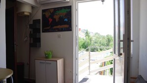 Une pièce dotée d’une porte-fenêtre coulissante donnant sur un balcon, d’un petit placard, d’une carte du monde accrochée au mur et d’un appareil de climatisation.