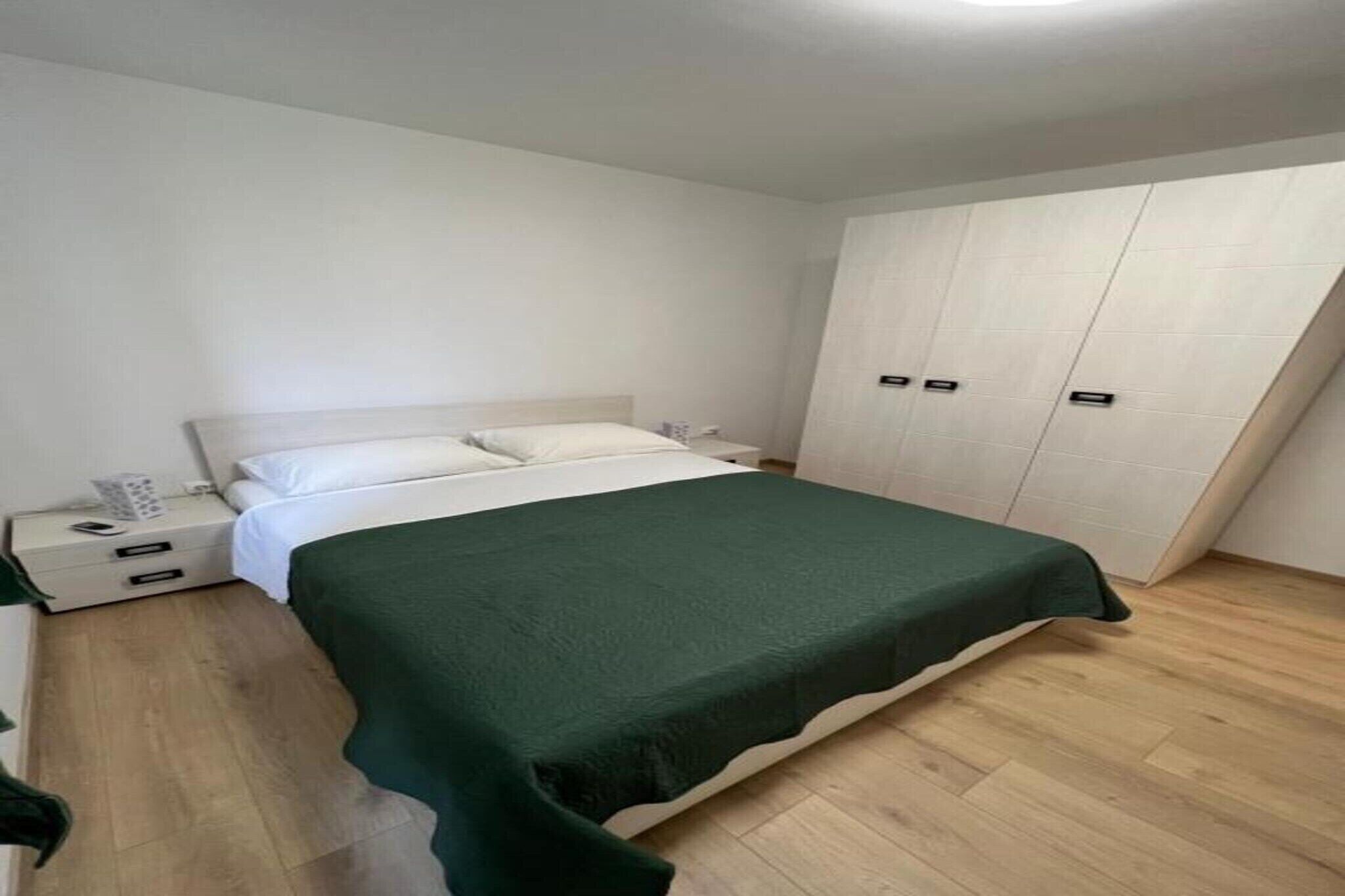Ein Schlafzimmer mit einem Bett, einem Nachttisch, einem Kleiderschrank und Holzboden.