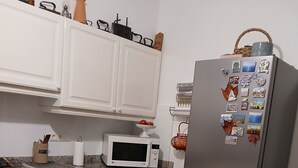 A kitchen with white cabinets, a microwave, a dishwasher, and a refrigerator with magnets. - T3 apartment (two bedrooms) on garden level, garden 120 m2 town center, (Saint-Jean-de-Luz)