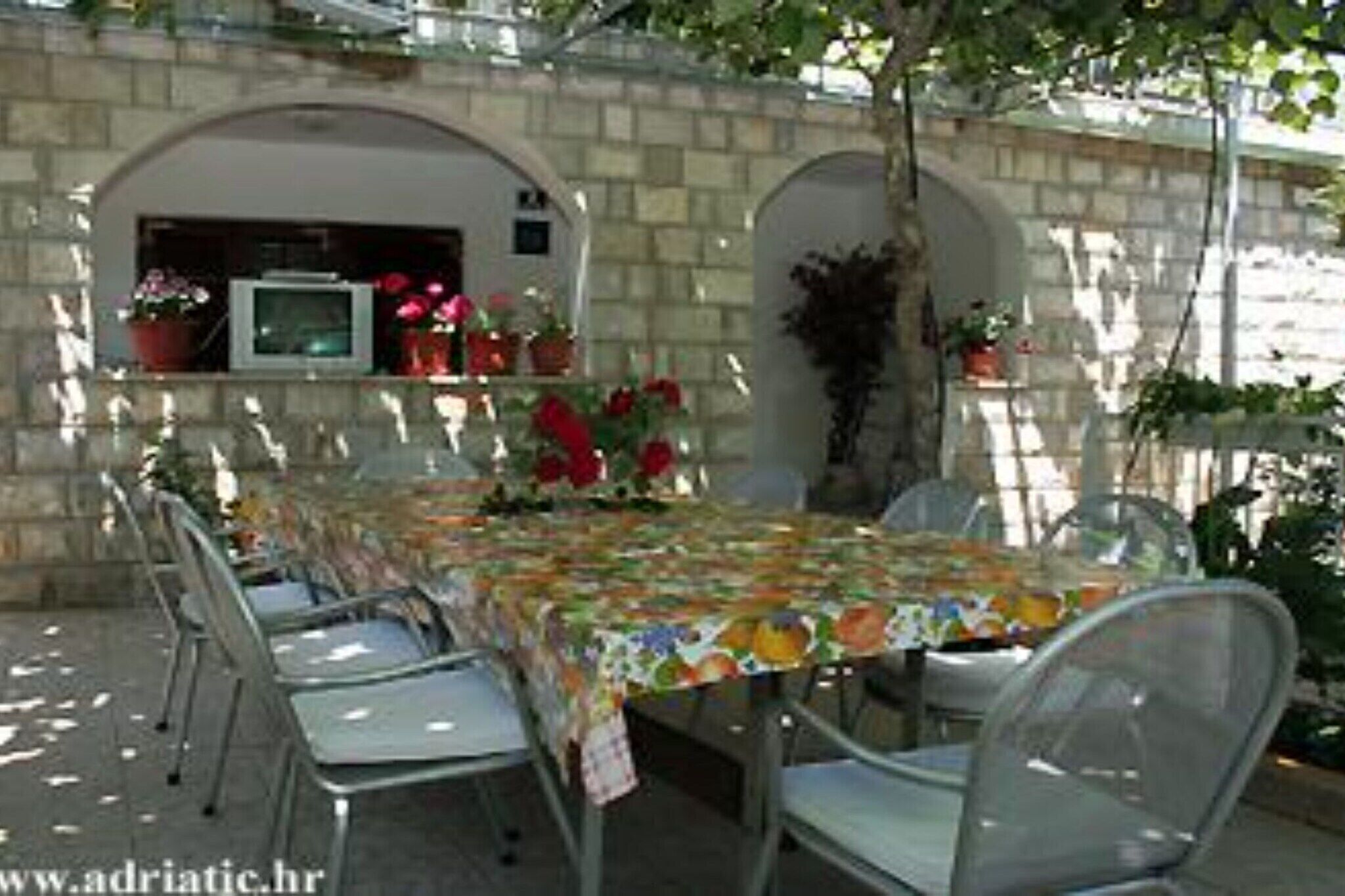 Zona pranzo all'aperto con un tavolo ricoperto da una tovaglia colorata, circondato da sedie in metallo.