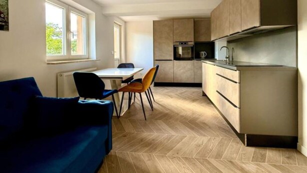 Eine moderne Küche mit Essbereich, einer Couch und einem Fenster, das für natürliches Licht sorgt.