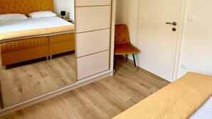 A bedroom with a bed, a chair, a wardrobe, and a mirror. - One-Bedroom Apartment With Terrace (Drace)