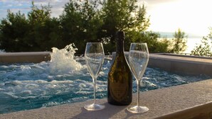 A hot tub with two champagne glasses and a bottle, surrounded by trees and a view of the water. - Two Bedroom Apartment with Sea View and Private Pool (Pisak)