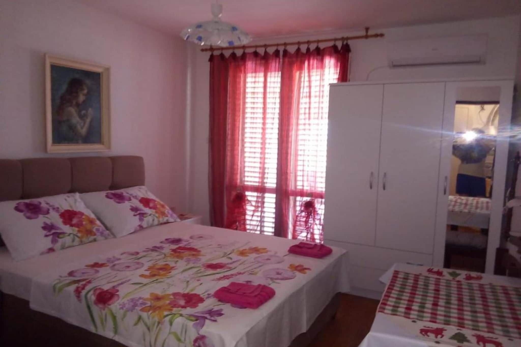 A bedroom with a bed, a wardrobe, a painting on the wall, and a window with curtains.