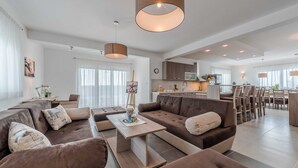 Een moderne woonkamer met een hoekbank, een salontafel en hanglampen.