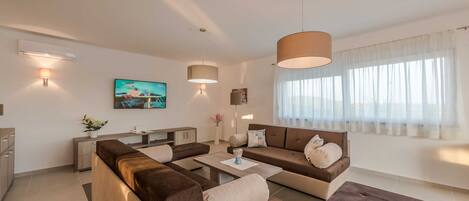 A modern living room with a sofa set, a coffee table, and a TV mounted on the wall.
