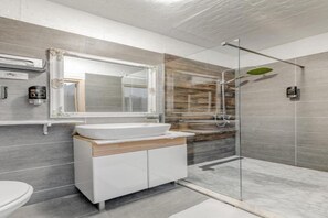 A modern bathroom with a glass shower enclosure, a large mirror, and a white sink.