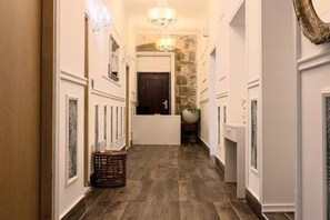 A hallway with a chandelier, a stone wall, and a door at the end. - Silver Gate Rooms-Diocletian's Palace - Six-Bed Room 1 (Split)