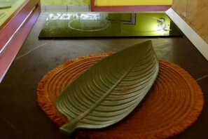 Un objeto con forma de hoja sobre un tapete naranja texturizado.