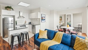 Un appartement moderne doté d’une kitchenette, d’un coin repas et d’un salon avec un canapé bleu.