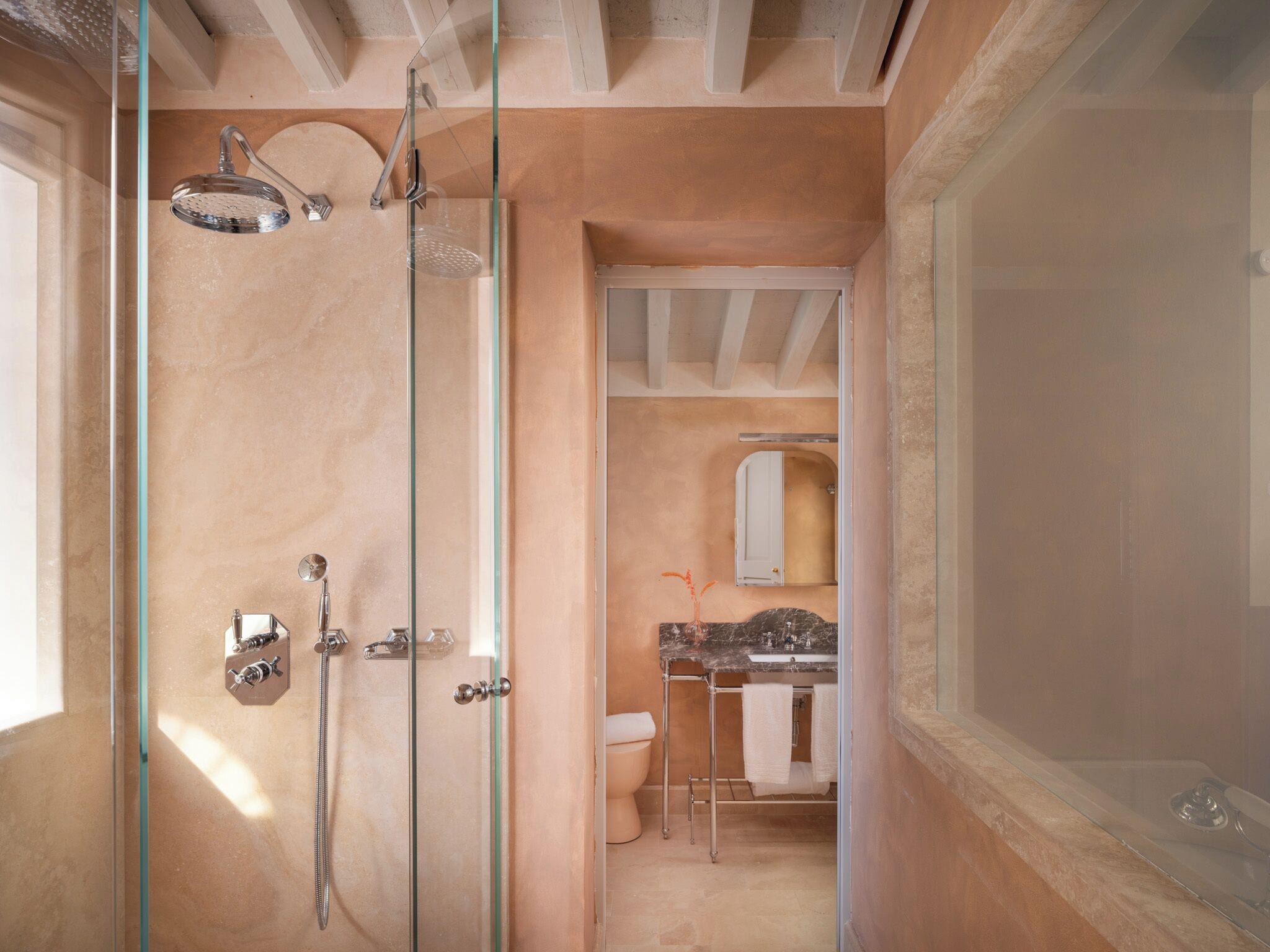 A modern bathroom with a glass-enclosed shower, a marble sink, and a toilet.