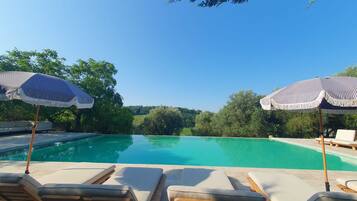 Alberca al aire libre, sombrillas en la alberca y camastros