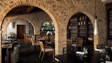 Un intérieur rustique avec des arches en pierre, des meubles en bois et un coin bar agrémenté de verres à vin.