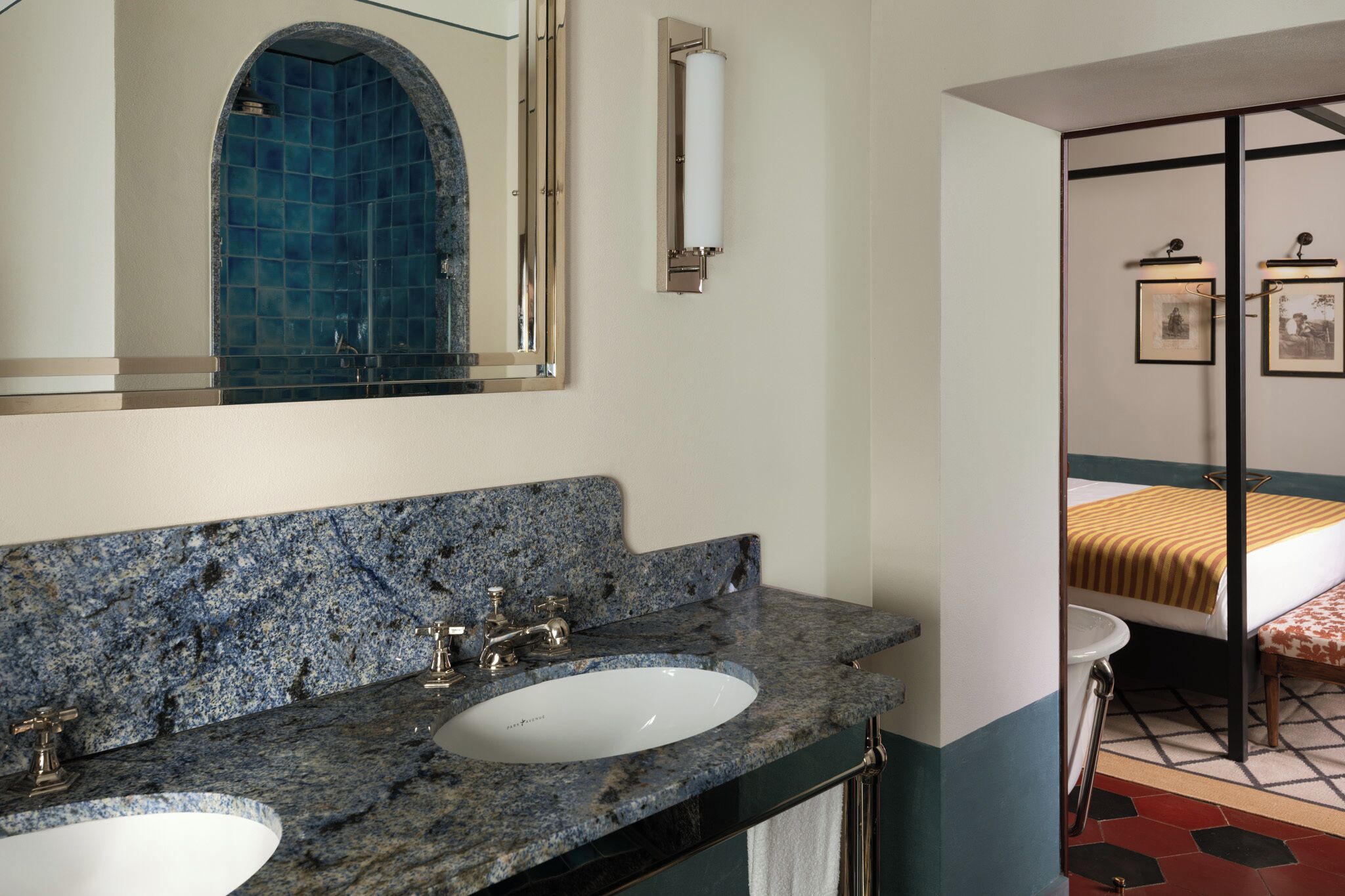 A bathroom with two sinks, a large mirror, and a shower with blue tiles.