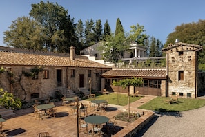 A courtyard with outdoor seating, stone buildings, and a clear sky.