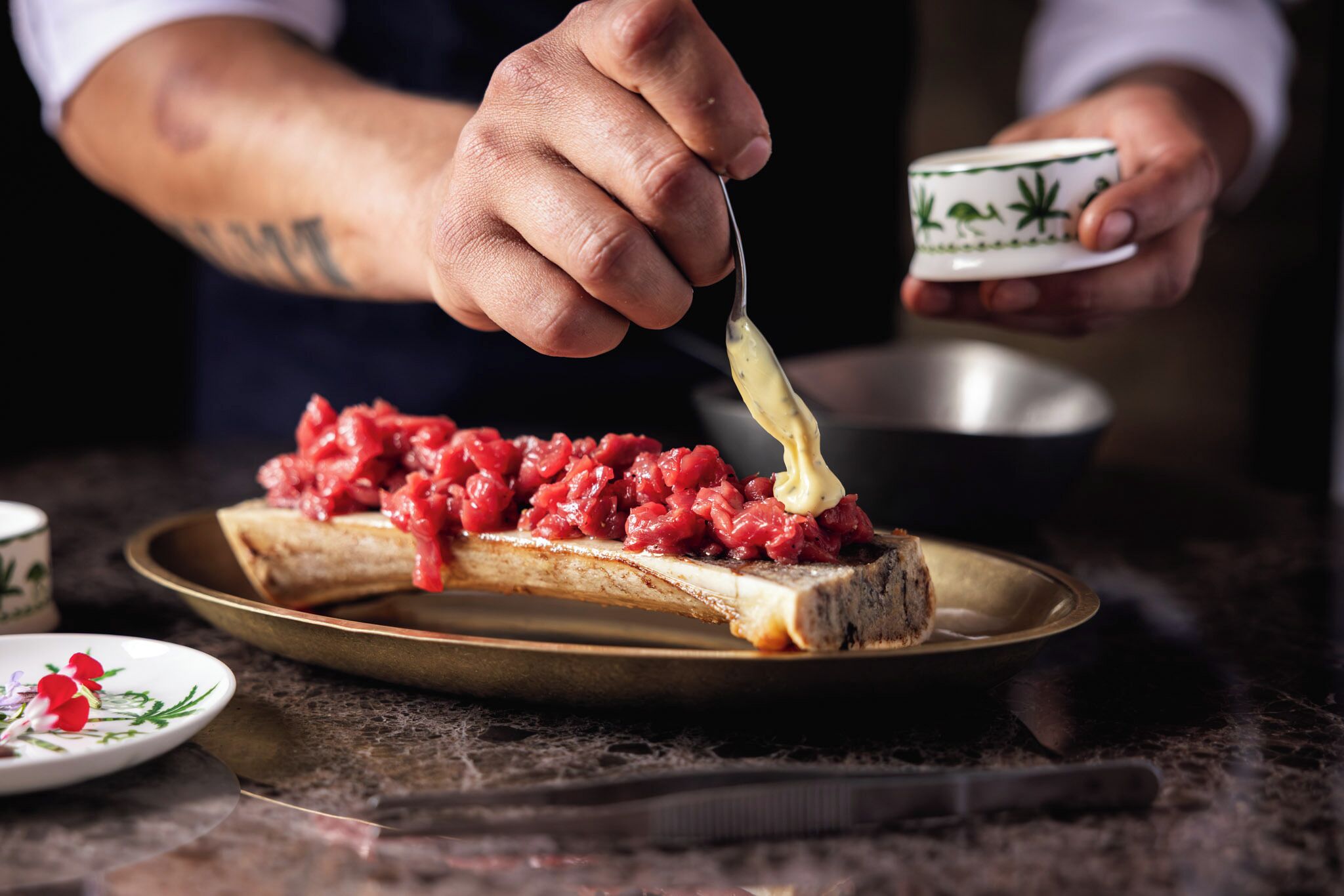 A person spreading a red paste on a slice of bread on a plate.