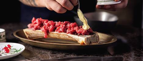 A person spreading a red paste on a slice of bread on a plate.