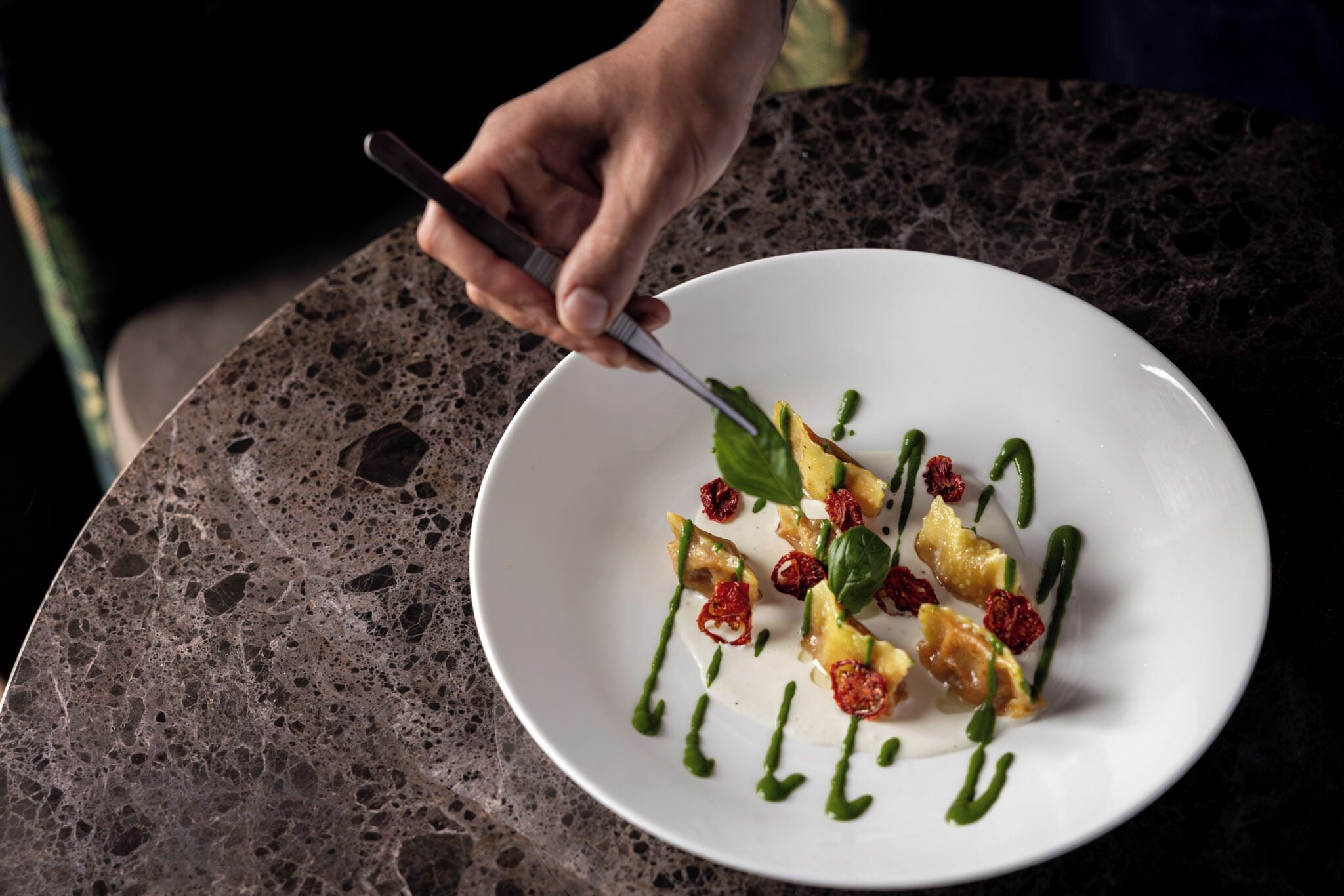 A white plate with food on a dark speckled surface.