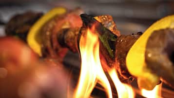 Un gril sur lequel on fait griller des aliments en broche au-dessus d’une flamme nue.