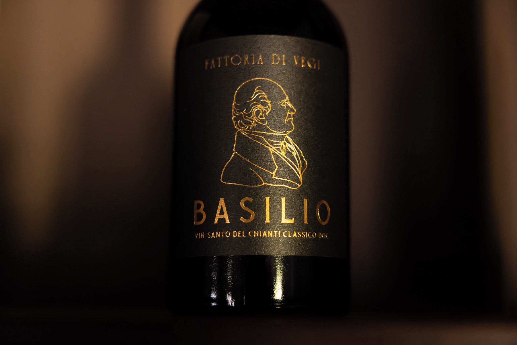 A wine bottle label with embossed text and a profile illustration.