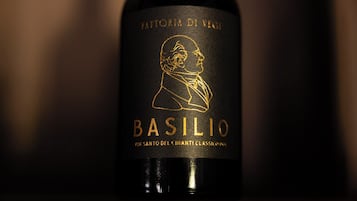 A wine bottle label with embossed text and a profile illustration.
