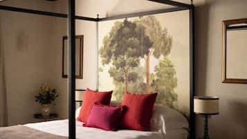 Un lit à baldaquin avec des oreillers rouges, un vase rempli de fleurs et un tableau encadré accroché au mur.
